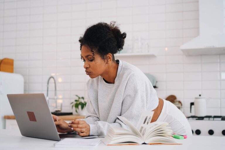Young woman studying digital marketing on a laptop at her kitchen table