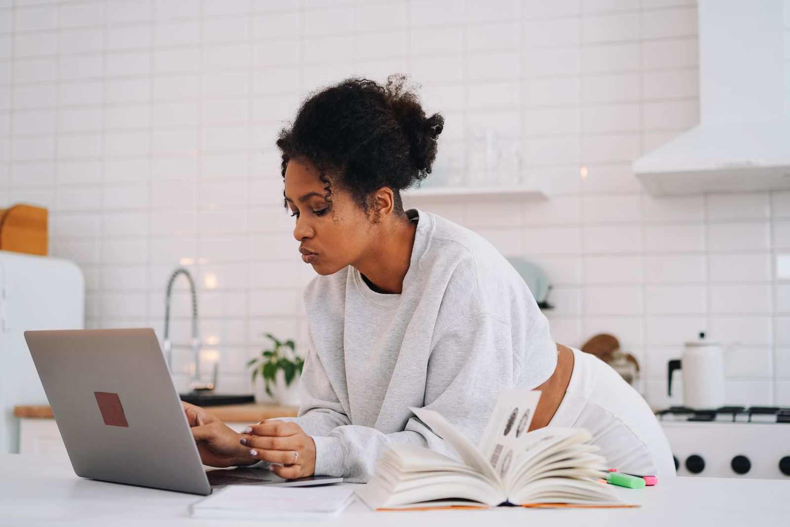 Young woman studying digital marketing on a laptop at her kitchen table